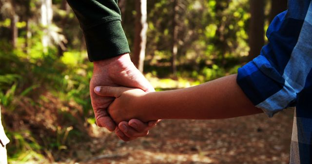 A close-up shows a child holding hands with an adult in a forest setting, with copy space. It conveys a sense of guidance and trust between generations amidst nature.