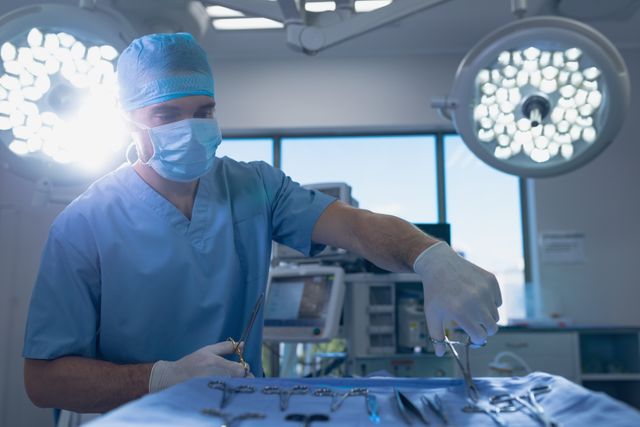 Male surgeon holding surgical instrument in operating room at hospital
