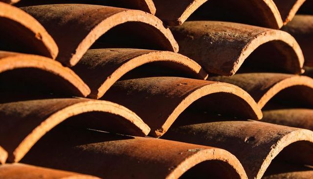 Stacking Terracotta Roof Tiles Forming Repeating Arches in Warm Sunlight