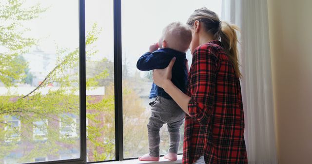 Mother Holding Baby Looking Out of Window on Sunny Day - Download Free Stock Images Pikwizard.com