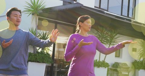 Couple practicing tai chi in sunlit patio