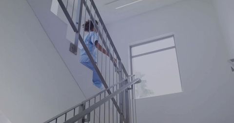 Healthcare professional in blue scrubs climbing stairwell