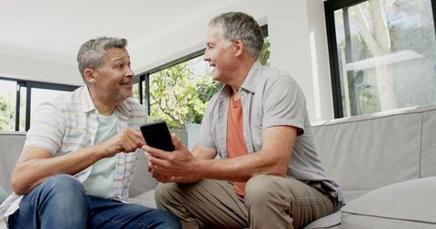 Senior Men Enjoying Technology Together on Sofa