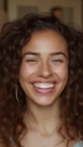 Making eye contact smiling and laughing woman with curly hair in intimate vertical video