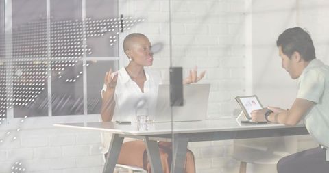 Female executive gesturing during collaborative meeting through glass partition