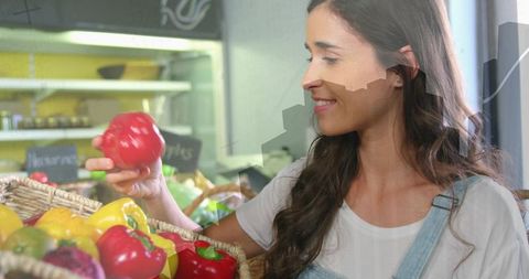 Young woman choosing red bell pepper at grocery market, healthy shopping lifestyle