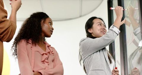 Diverse professionals collaborating at digital whiteboard in modern office