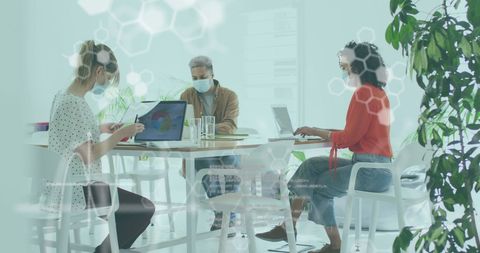 Colleagues Collaborating with Digital Interface Elements, Wearing Masks in Office Environment