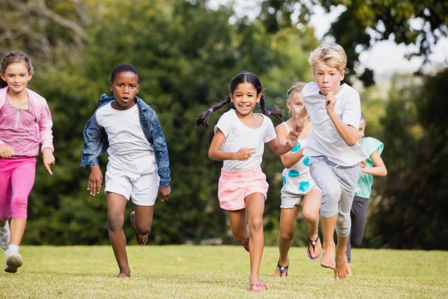 Children are running and playing together in a park on a sunny day. They appear to be having fun and enjoying outdoor activities. This image can be used for promoting outdoor activities, healthy lifestyles for children, summer camps, and community events.