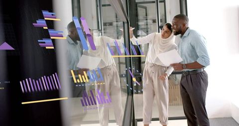 Diverse Business Team Analyzing Charts and Data on Glass Wall