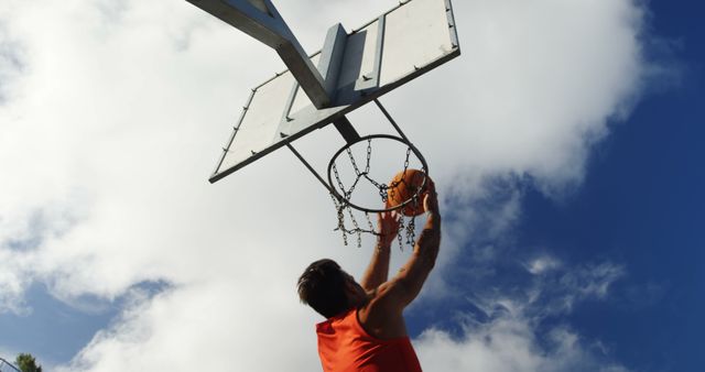 Young Man Dunks Basketball on Outdoor Hoop Against Blue Sky - Download Free Stock Images Pikwizard.com