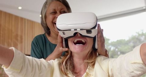 Senior Mother Helping Daughter Explore Virtual Reality Gaming