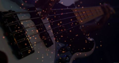 Plucking bass guitar strings musician's hand with star bokeh moody purple-blue lighting