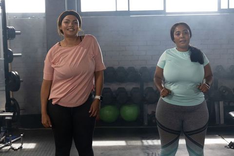 African american women exercising together at dumbbell rack in industrial gym