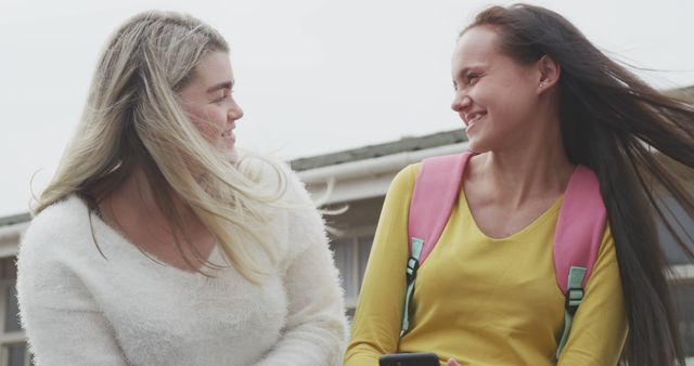 Two Young Women Smiling Outdoors in a Friendly Conversation - Download Free Stock Images Pikwizard.com