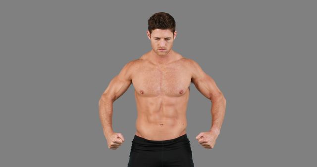 A young Caucasian male with a muscular build poses confidently, showcasing his physique, with copy space. His stance and expression convey strength and determination, often associated with fitness or bodybuilding.