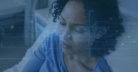Curly woman studying with blue augmented reality hud overlay on sofa, digital learning focus