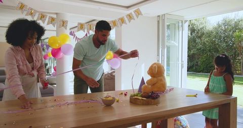 Diverse family preparing birthday party with joyful decorations