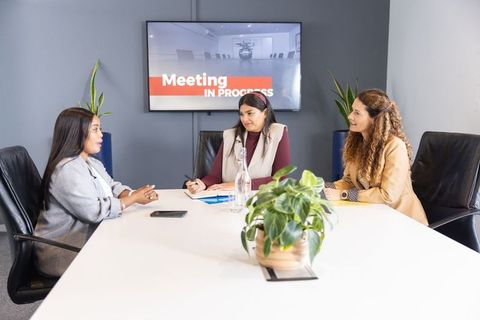 Diverse female professionals reviewing documents and collaborating in modern boardroom