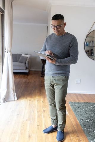 Senior Man in Modern Living Room Using Tablet for Relaxation