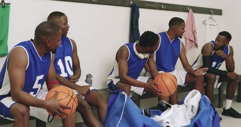 Basketball team chatting on locker room bench sharing strategy and camaraderie