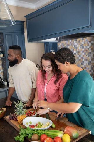 Diverse friends preparing fruit salad in modern kitchen