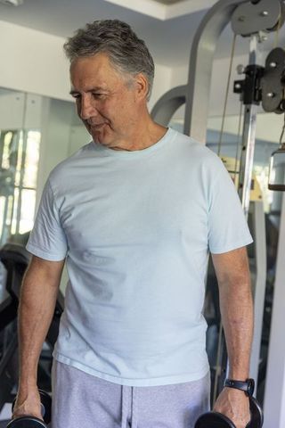 Senior man lifting dumbbells in home gym building strength and healthy active aging