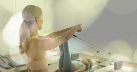 Pilates instructor pointing and guiding client on reformer for focused core strength