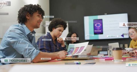 Design team collaborating around table reviewing app mockups with augmented overlays