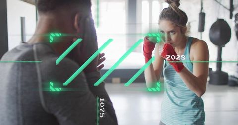 Training female athlete throwing punches with coach mitts and digital HUD fitness overlay