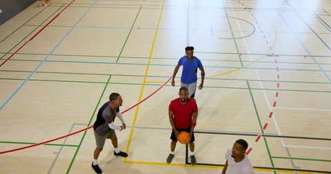 Holding basketball and preparing to pass during indoor pickup game on hardwood court