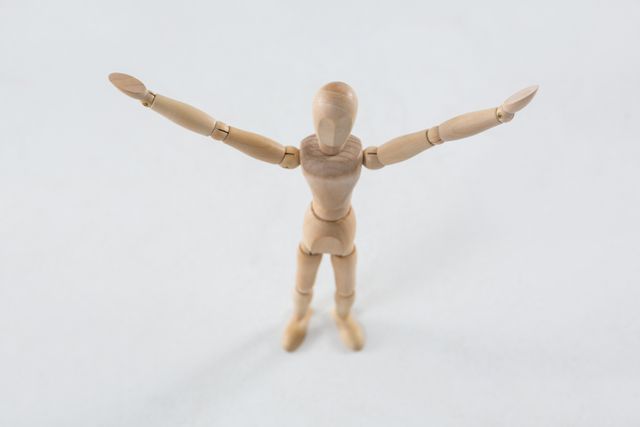 Wooden figurine standing on wooden floor with arms spread