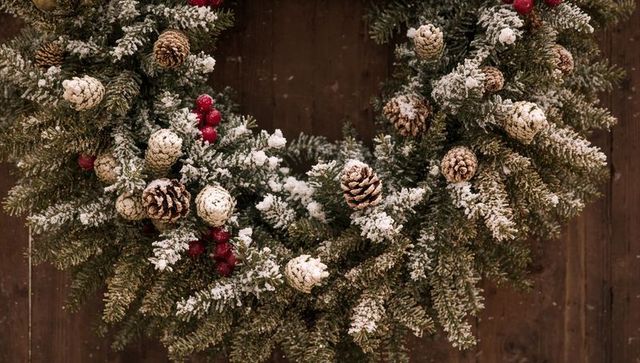 Snow-Dusted Fir Wreath Featuring Pine Cones and Red Berries on Rustic Wooden Door
