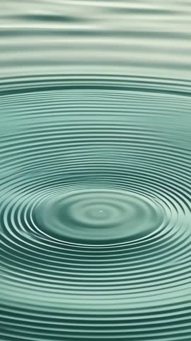 Droplet falling, creating concentric rings in teal water, tranquil vertical motion loop