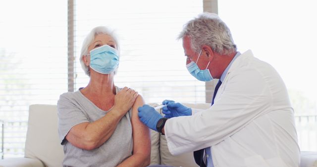 Doctor administering vaccine to elderly patient wearing mask. Ideal for health care campaigns, vaccine information, medical procedures, senior care, and preventive health measures.