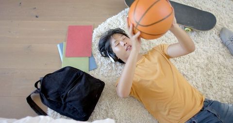 Relaxed Teenager Lying Down with Basketball and Books