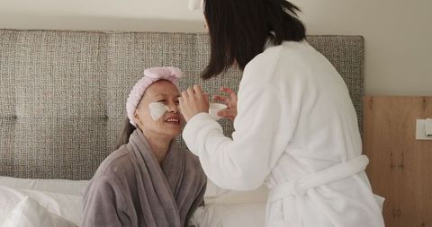 Daughter Applying Facial Cream to Senior Mother in Relaxing Bedroom Scene