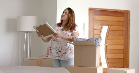 Woman unpacking in new home imagining decoration