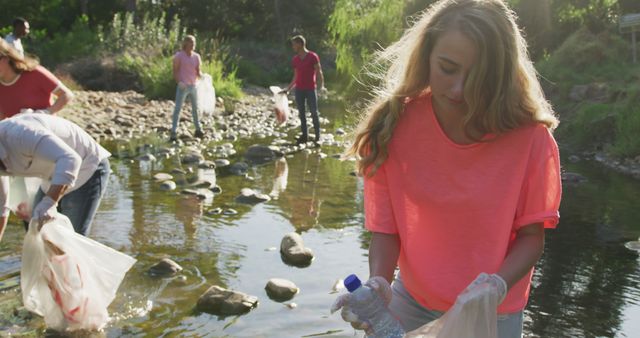 Volunteers, including a Caucasian woman, clean a river in a sunny rural eco-initiative. - Download Free Stock Photos Pikwizard.com