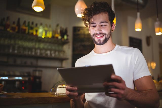 Smiling man using digital tablet in cafe