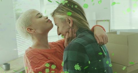 Tender same-sex couple embracing during move in cozy living room with green clover overlay