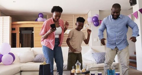 African American Family Dancing at Home Celebrating Birthday with Cupcakes and Balloons