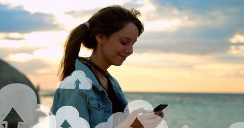 Smiling Woman Using Smartphone on Beach at Sunset