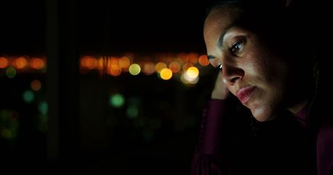 Pensive businesswoman sitting at desk with cityscape background