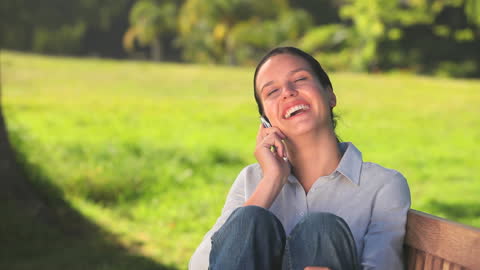 Woman Enjoying Phone Conversation Outdoors on Sunny Day