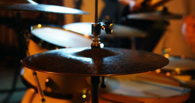 Showing drum kit close-up during live concert in warm lighting. Ideal for use in articles, blogs, and promotional material on music concerts, live performances, and instruments. Can be used in marketing campaigns for music events, illustrative content for musician profiles, or educational content on percussion instruments.