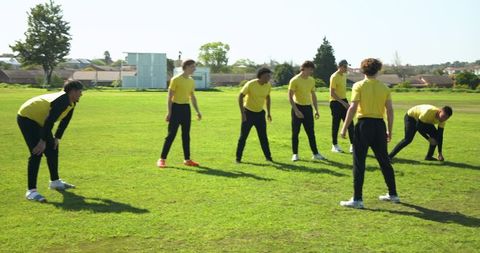 Male Athletes Warming Up on Grassy Sports Field in Semicircle