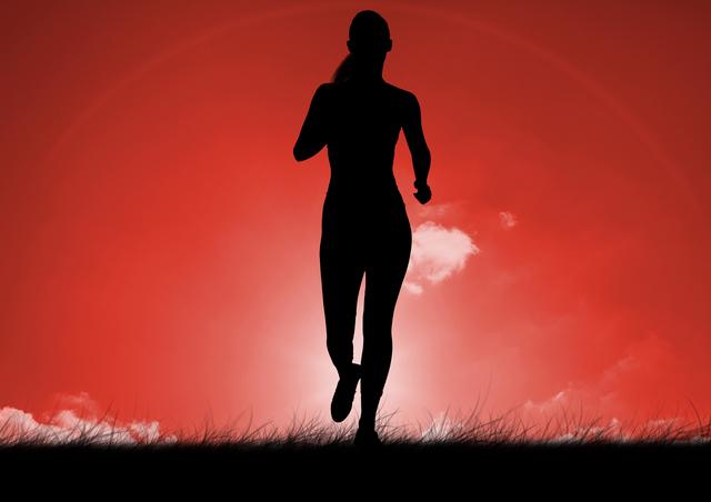 Silhouette of a woman running on grass with a vibrant red sunrise in the background. Great for fitness and health-themed projects, motivational posters, articles about morning workouts, and promoting outdoor exercise.