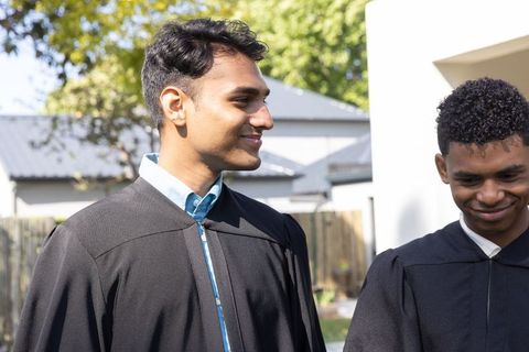 Happy Graduates Celebrating Together Outdoors in Black Gowns