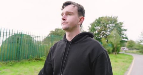 Man Running Outdoors in Black Hoodie Focusing on Fitness